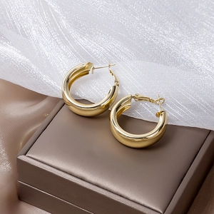 Close-up of chunky gold hoop earrings displayed on premium dark jewelry box