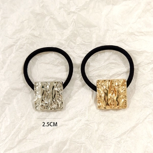 Detail of 2.5cm square gold and silver metal hair ties with hammered texture finish