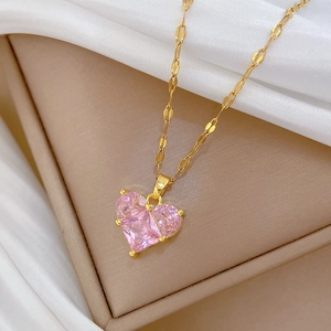 Detail view of heart-shaped pink gemstone pendant on a golden curb chain necklace