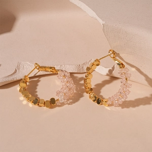 Détail des pierres de cristal roses et des perles dorées sur les boucles d'oreilles