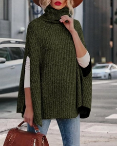 Dettaglio di un maglione poncho a collo alto verde scuro con spessa trama a maglia grossa