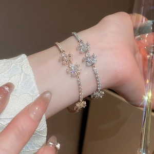 Close-up of sparkling zircon flower charm bracelets in gold and silver on female wrist
