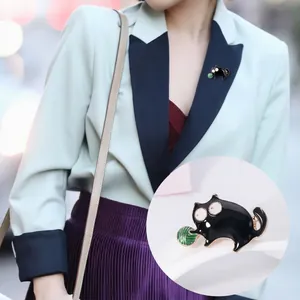 Close-up of black alloy cat brooch with green enamel ball detail on blazer