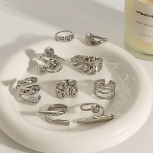 Set of eight minimalist silver geometric rings displayed on a white ceramic jewelry tray