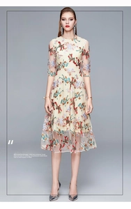 Close-up of intricate colorful floral embroidery on elegant beige mesh party dress