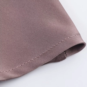 Detailed close-up of the fine stitching and mauve satin fabric texture of the dress