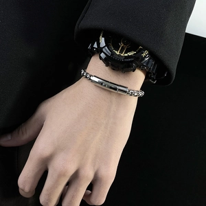 Close-up of a minimalist silver stainless steel chain bracelet on a male wrist with watch