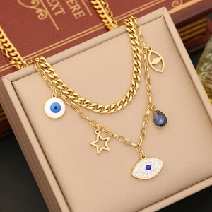 Detail of layered gold necklace featuring evil eye, star charms and blue gemstone pendant