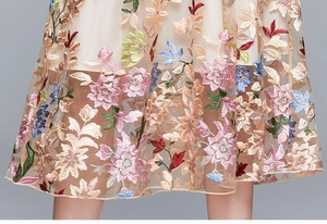 Close-up of vibrant 3D floral embroidery on elegant high-waisted beige mesh dress fabric