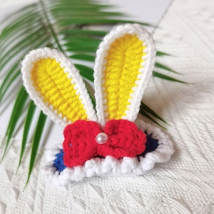 Detail of handmade crocheted rabbit ear hair clip with yellow ears and a pearl accent