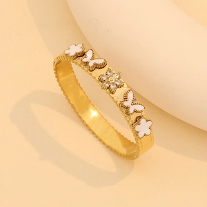 Golden stainless steel bangle featuring white clover, butterfly charms and crystal flower