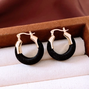 Gros plan de boucles d'oreilles créoles dorées avec flocage velours noir en écrin