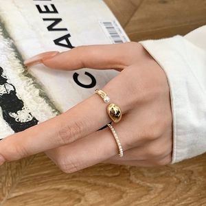 Macro shot of two gold plated pearl rings featuring minimalist wrap and beaded designs