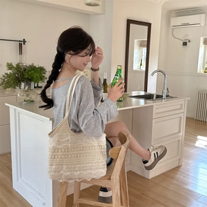 Détail du grand sac cabas en dentelle crochetée blanche porté par un mannequin en intérieur