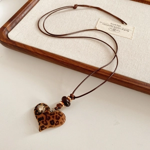Détail du pendentif cœur avec motif léopard et strass sur un cordon en cuir marron