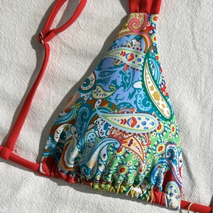 Detailed macro view of colorful paisley pattern bikini top with red adjustable straps
