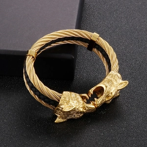 Macro detail of golden wolf head design on a braided steel and leather mens bracelet