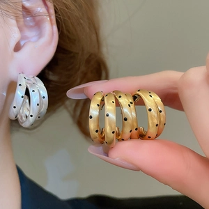 Dettaglio degli orecchini a C placcati in oro 18k con superficie a pois e finitura spazzolata