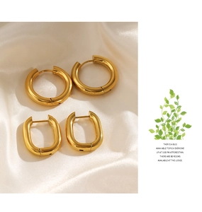 Detail of two pairs of minimalist gold geometric earrings on smooth white silk fabric