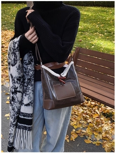 Close-up of brown faux leather shoulder bag with white fleece trim and toggle closure