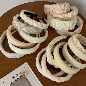 Elegant cream headband collection with satin, pearl, and woven details on a wooden table