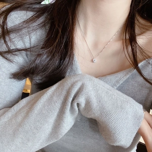 Detail of a minimalist square diamond pendant necklace worn on a collarbone for women