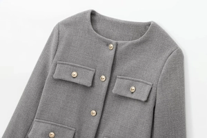 Detailed close-up of grey tweed texture and decorative gold buttons on a crop blazer