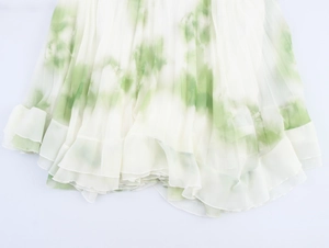 Detail of white pleated chiffon skirt with fresh green tie-dye print and wavy hemline