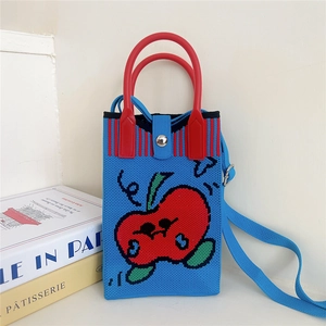 Detailed shot of a blue knitted apple bag with a red handle and magnetic closure on books