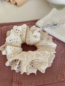 Détail du chouchou en dentelle brodée blanc crème sur tissu en velours côtelé