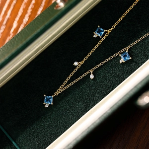 Elegant gold necklace with square blue zircons and crystals in a green velvet box
