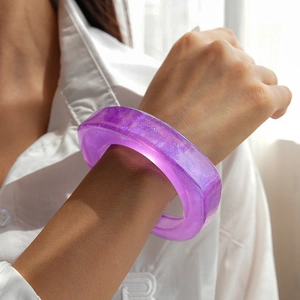 Detail of a thick purple resin cuff bracelet featuring glittering sand particles