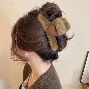 Detail view of a plush brown heart hair claw clip styled on a woman's hair bun