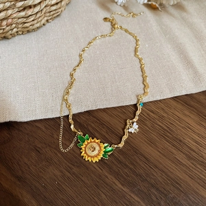 Detail of sunflower necklace with bee charms on a rustic wood and linen background