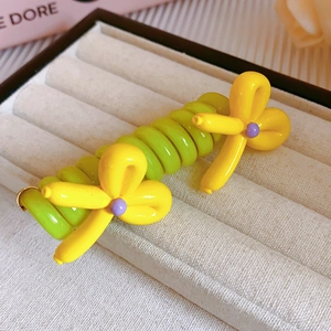 Détail d'élastique spirale vert avec fleur jaune style ballon et perles violettes