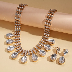 Détail d'une parure collier dorée luxueuse avec strass blancs et pendentifs gouttes