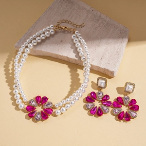 Detail of double-layer faux pearl necklace with pink gemstone flower pendant and earrings