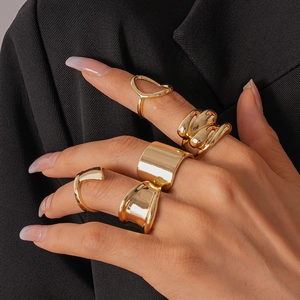 Detail of five-piece gold chunky geometric rings worn on hand against a black suit