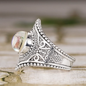 Gros plan sur une bague vintage en argent gravée avec pierre de lune iridescente