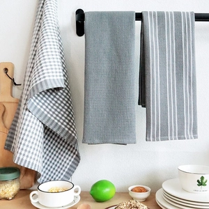 Close-up of grey waffle weave and striped cotton kitchen towels hanging on a rack