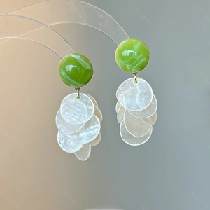 Détail de boucles d'oreilles en résine vert émeraude avec pendentif en nacre