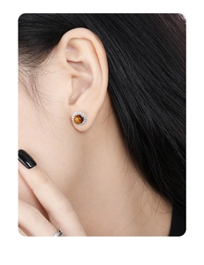 Detailed view of round tiger eye stud earrings with micro-pave cubic zirconia on a model