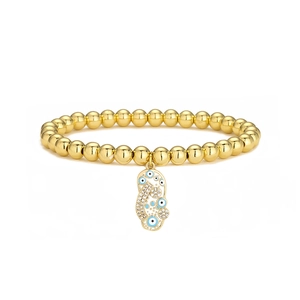 Macro detail of 18K gold-plated beaded bracelet with blue enamel evil eye charm and zircons