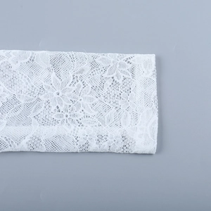 Primo piano dei polsini in pizzo floreale bianco con trame a maglia e motivi a petali