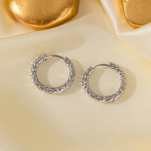 Detailed view of silver hammered texture titanium steel hoop earrings on silk fabric