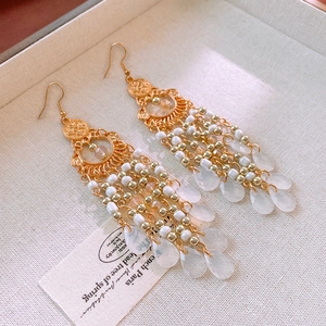 Detailed macro view of bohemian tassel earrings with gold beads and crystal water drops