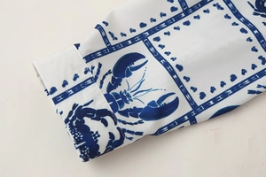 Detailed macro view of the shirt cuff showing blue lobster print on white woven fabric