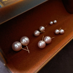 Macro shot of minimalist champagne pearl stud earrings set in four gradient sizes