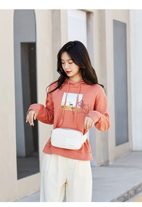 Coral orange hoodie and white monogram fanny pack styled on a model for outdoor fashion