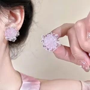 Detailed view of pink flower stud earrings with matte resin petals on model's ear